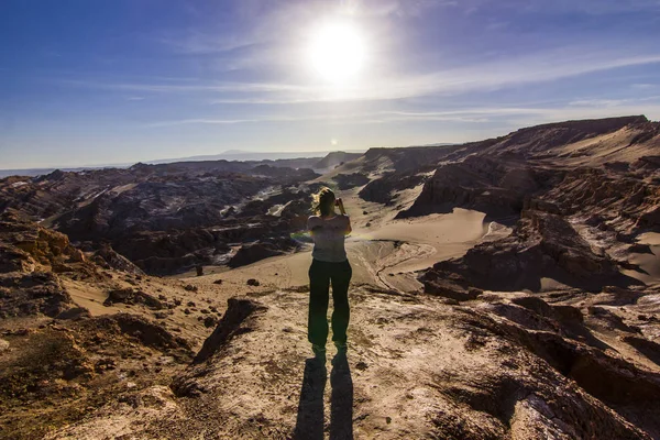 Girl standing on a cliff in salty Moon valley in atacama desert at sunset — Stock Photo, Image