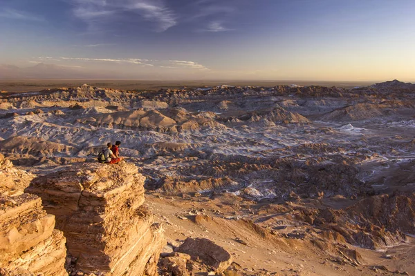 Mężczyzna siedzący na klifie w słony Moon valley w pustyni atacama o zachodzie słońca — Zdjęcie stockowe