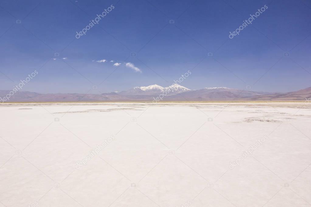 white saline of laguna rossa in atacama desert surrounded by high peaks