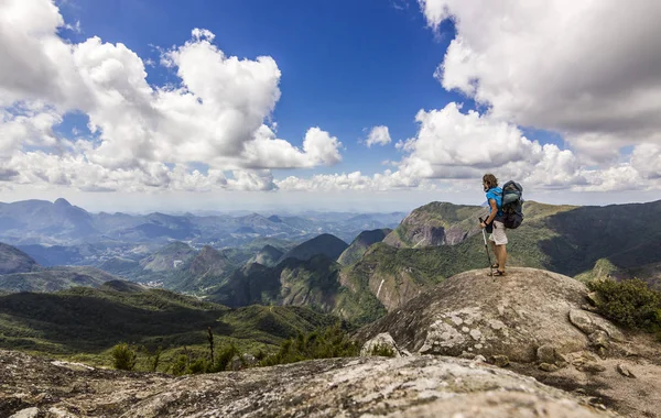 Man met rugzak staande op de top van berg met blauwe hemel met wolken — Stockfoto