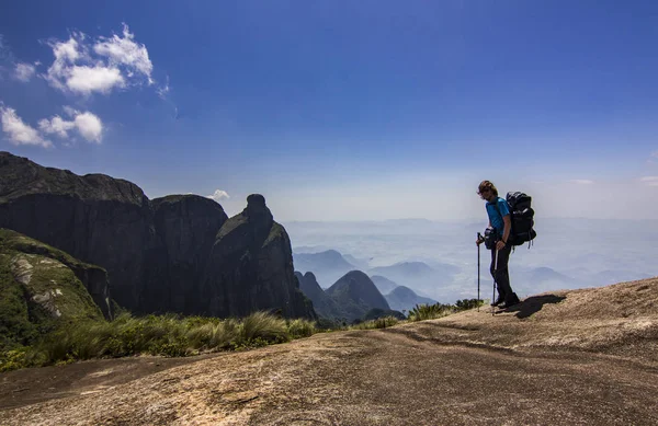 Man met rugzak staande op de top van berg met blauwe hemel met wolken — Stockfoto