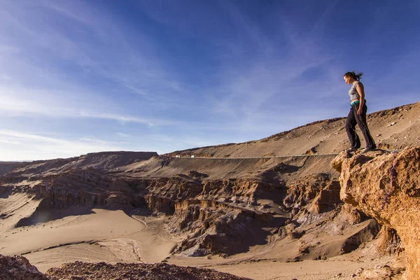 Chica de pie en un acantilado en el valle de la Luna salada en el desierto de atacama al atardecer — Foto de Stock