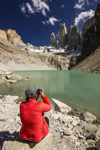 Dziewczyna w czerwonej kurtce siedzi na kamieniu nad jeziorem w Patagonii — Zdjęcie stockowe