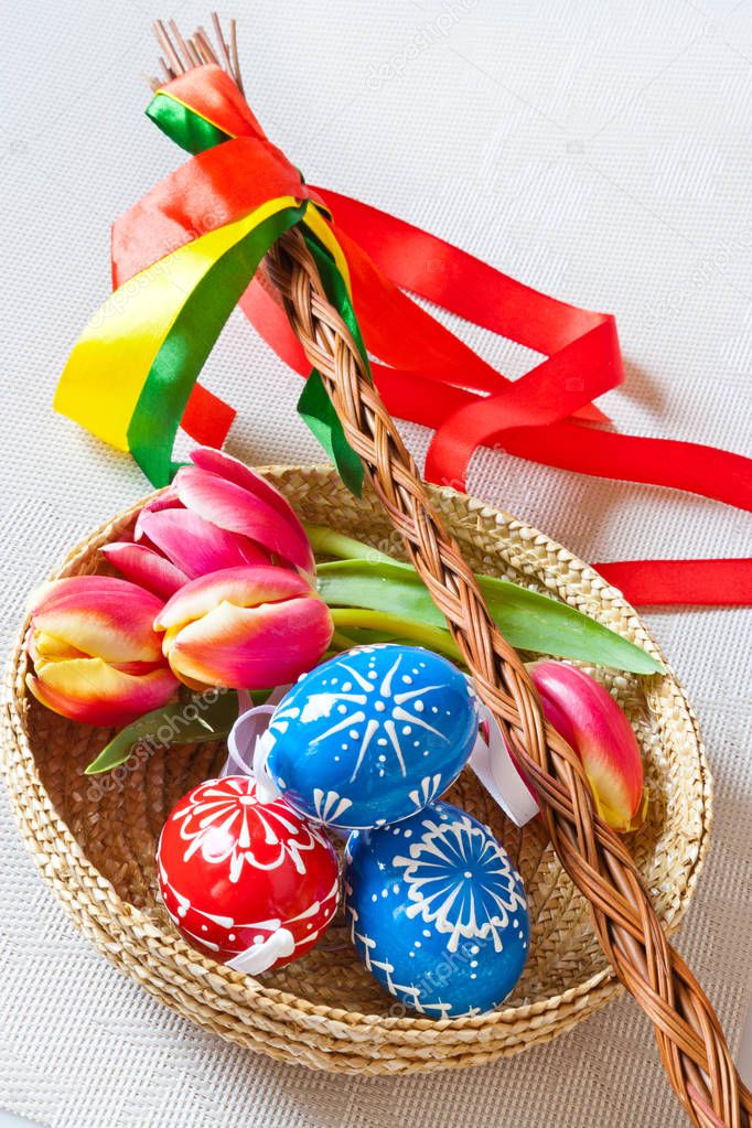 Traditional Czech easter decoration - regional whip with ribbons with tulip and decorated red eggs in the wicker scuttle. 