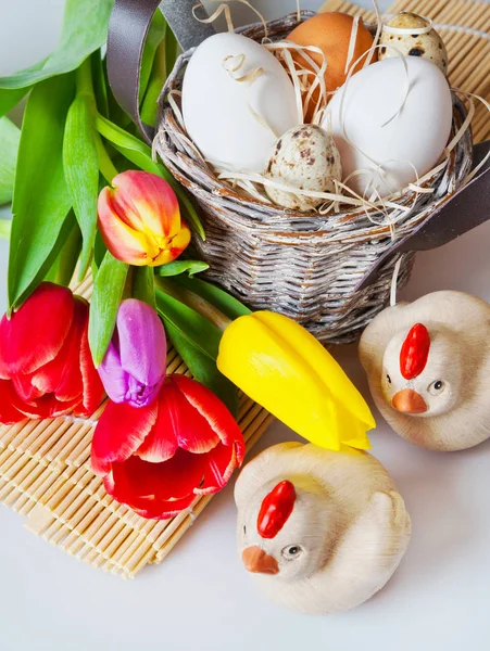 Traditional Czech easter decoration - white eggs with tulip flowers in the basket nest, quail eggs and wooden chickens.