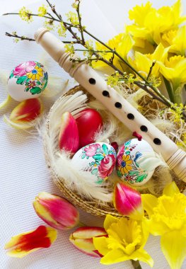 Geleneksel Çek Paskalya dekorasyon - tahta flüt müzik enstrümanı nergis ve Lale çiçek beyaz tüylü yuva ile boyalı yumurta ile. Paskalya tatili aranjman bahar.