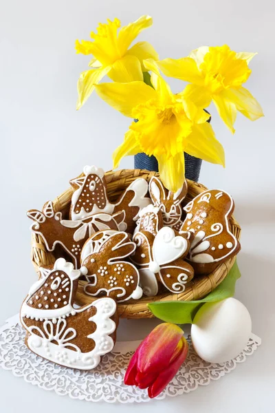 Traditional Czech easter decoration - my own homemade regional gingerbread cakes in the wicker nest with tulip and daffodils flowers on white background. Spring easter holiday arrangement. — Stock Photo, Image