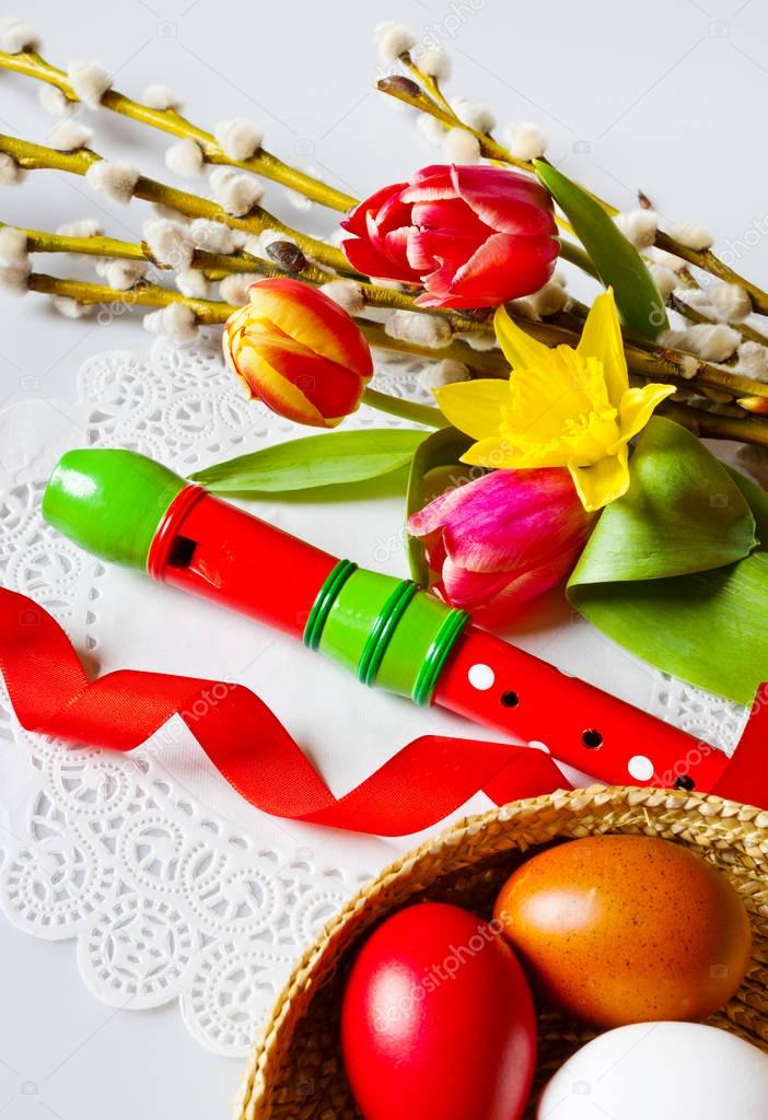 Traditional Czech easter decoration - my handmade painted eggs with daffodils, tulip and pussycats flower and wooden music instrument flute. Spring easter holiday arrangement.