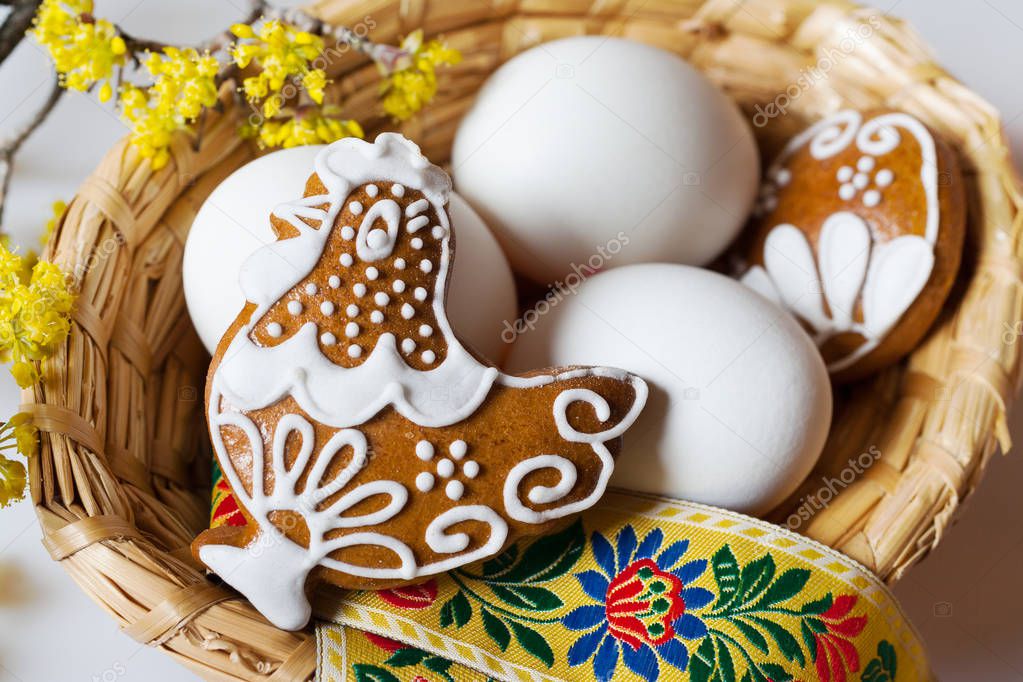 Traditional Czech easter decoration - white eggs in wicker nest with decorated gingerbread hen cake with dogwood flower. Spring easter holiday arrangement.