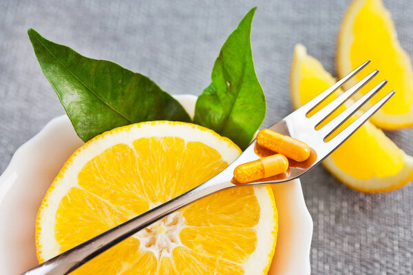 health care and wellness - fresh orange fruit and vitamin C as tablets, grippe and other illnesses prevention