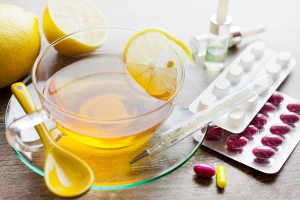 Мед черный чай с лимоном и различные лекарства против гриппа и гриппа - здравоохранение и оздоровление - различные таблетки и шприц вакцинации — стоковое фото