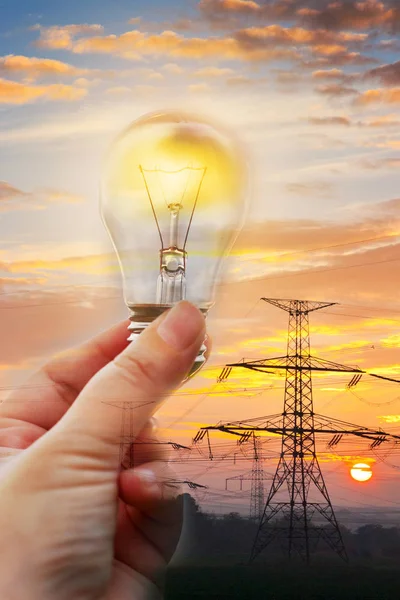 Electrical energy - hand holding a shining bulb - energy savings and expenses concept - environmental protection