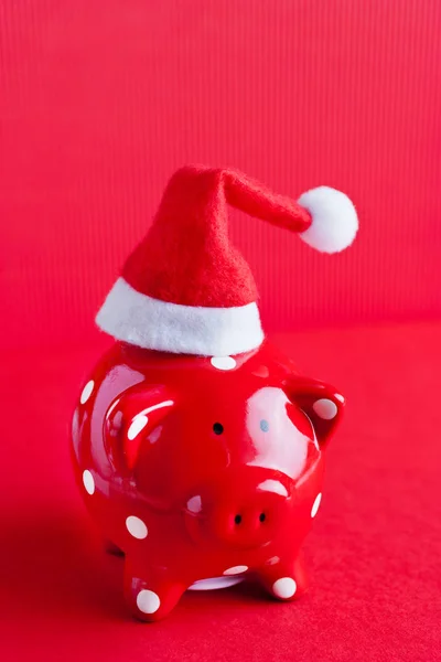 red Piggy bank with polka dots on red background with Santa Claus hat