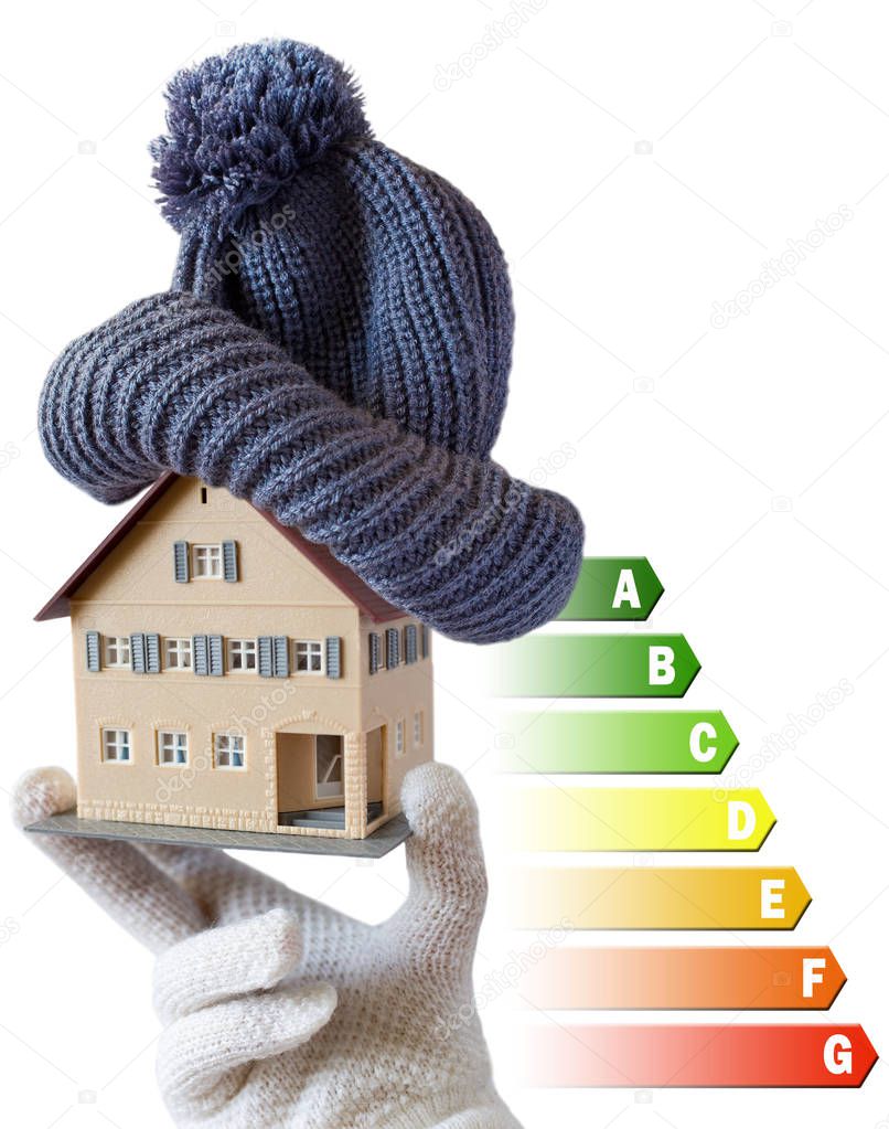 Energy efficiency label for house / heating and money savings - model of a house with cap in a hand in gloves