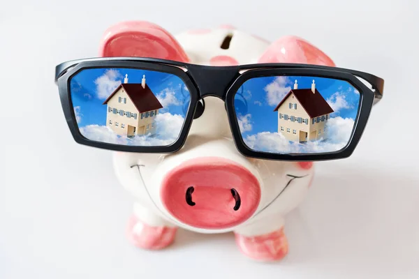 Economy and finance - piggy bank with glasses and dreamed house - savings for a new house — Stock Photo, Image