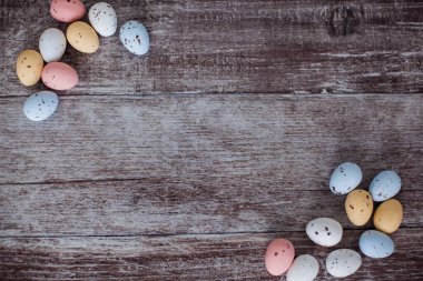 Ahşap arka planda pastel renkli paskalya yumurtaları. Paskalya kartı için boş. Metnin için yer.