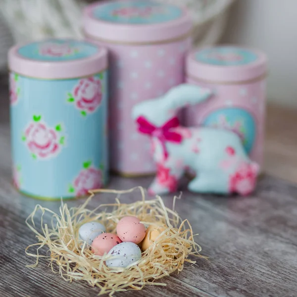 Multi-colored Easter eggs in nest on wooden background. Happy Easter card