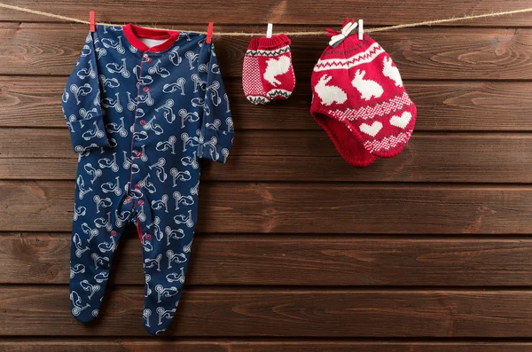 Roupas de bebé (fato de dormir, chapéu de malha e luvas) penduradas — Fotografia de Stock