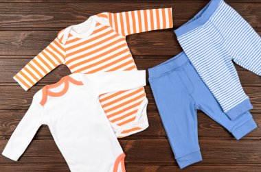 İki bebek bodysuits ve ahşap zemin üzerine pantolon. Bebek giydirin