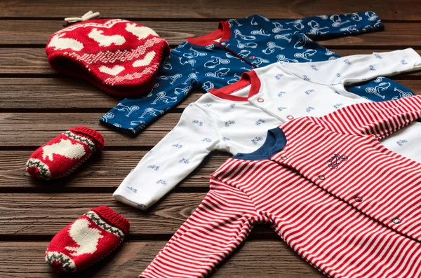 Roupas de bebé (fatos de dormir, chapéu de malha e luvas) em castanho — Fotografia de Stock