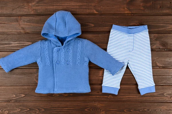 Bebês azul de malha cardigan e calças listradas no backgro de madeira — Fotografia de Stock