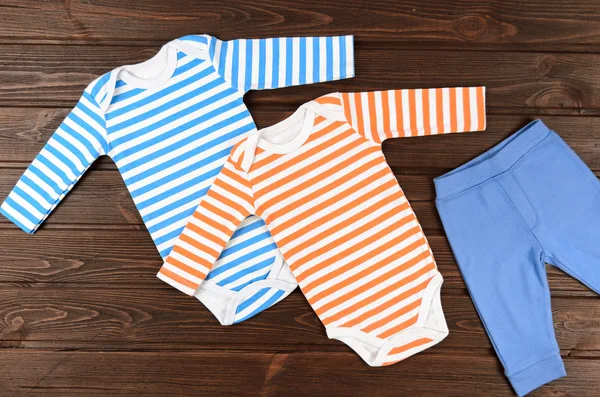 Bebês bodysuits e calças em fundo de madeira. Roupas de bebê — Fotografia de Stock