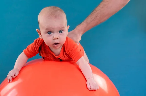 Aranyos baba kék alapon narancs fitball feküdt. Co — Stock Fotó