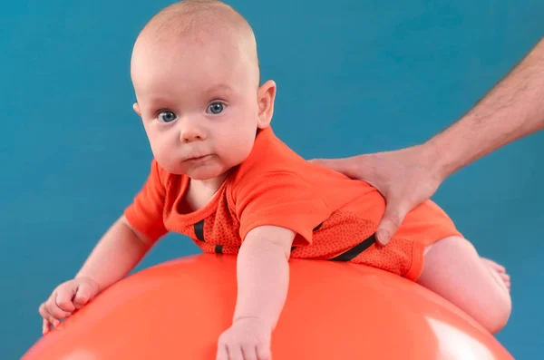 Aranyos baba kék alapon narancs fitball feküdt. Co — Stock Fotó
