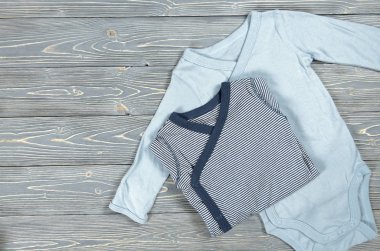 İki mavi bebek bodysuits gri ahşap zemin üzerinde. Alışveriş anne