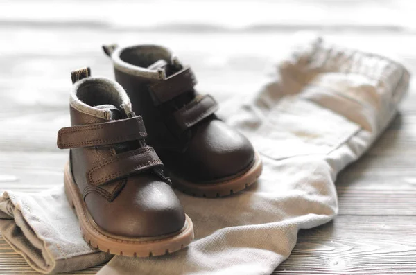 Scarpe per bambini in pelle marrone e pantaloni in denim su sfondo di legno — Foto Stock