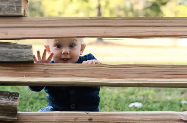 Um rapazinho escondido atrás de uma cerca. Conceito de jogo atividade ao ar livre . — Fotografia de Stock