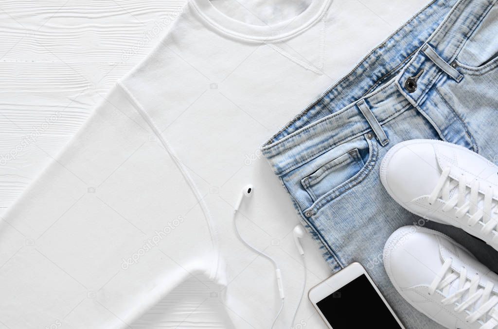 Womens fashion white clothing, shoes, accessories (white leather sneakers, blue jeans, sweatshirt, headphones. Fashion concept. View from above, Flat lay. Spring summer collection. casual style
