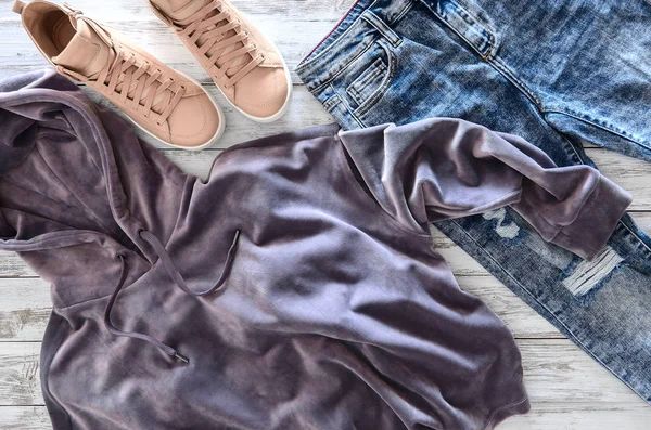 Женская одежда, обувь (фиолетовая бархатная толстовка, кислотная мойка джинсов) — стоковое фото