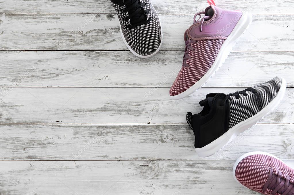 Two pairs of sneakers (violet, black and white)  on wooden backg