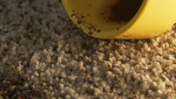 Taza amarilla de café cayendo sobre alfombra gris sin costura, primer plano te — Foto de Stock