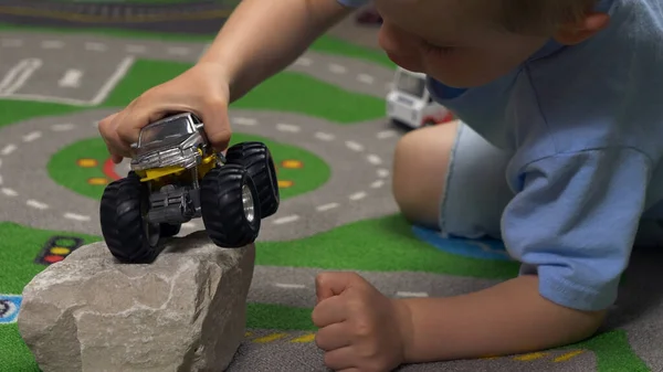 Little boy playing with toy truck car in his room alone. Child playing with toys (cars, trucks) indoor. Activities for kids at home