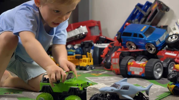 Little boy playing with toy truck car in his room alone. Child playing with toys (cars, trucks) indoor. Activities for kids at home
