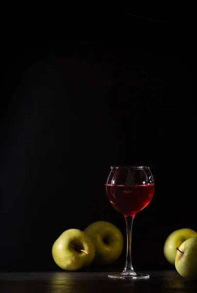 A glass of red fruit wine isolated on black. Apples fresh crop, still life in a low key. Copy space. Banner for cafe, winery and restaurant.