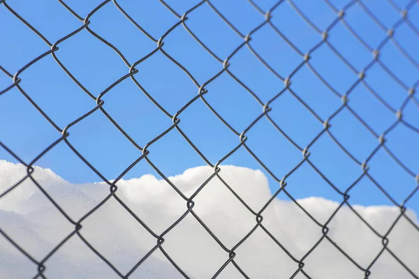 El alambre de malla con nieve y cielo helado . — Foto de Stock