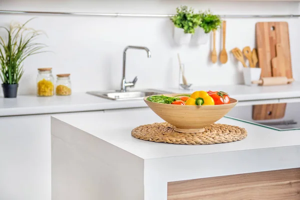 Interior da cozinha branca moderna com aquecedor de cozinha por indução e legumes na mesa — Fotografia de Stock