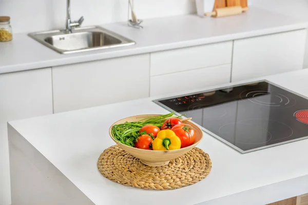 Closeup zeleniny v misce v moderní bílá kuchyňská linka s Indukční vaření ohřívač a jímka na pozadí — Stock fotografie