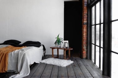 Endüstriyel açık alan tavan arası. Gün ışığıyla dolu büyük pencereli bir yatak odası.