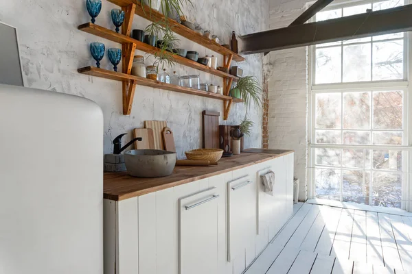 Geniş, endüstriyel, açık, mutfak stüdyosunun iç tarafında mutfak aletleri ve büyük pencereler var.