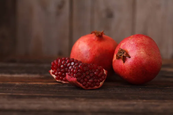 Fruta de granada jugosa sobre fondo de madera en estilo rústico —  Fotos de Stock