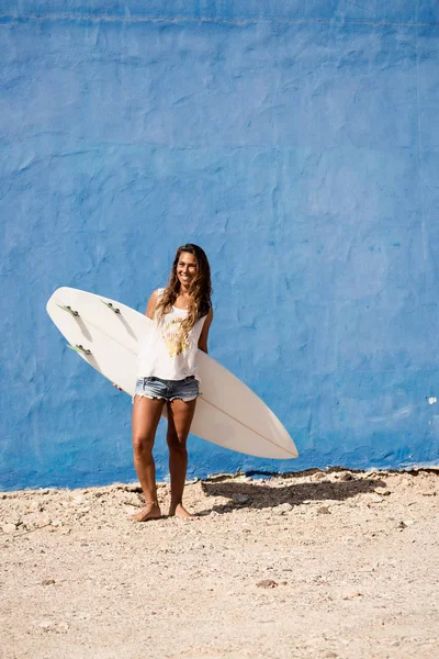 Felice surfista ragazza con tavola da surf davanti al muro blu — Foto Stock