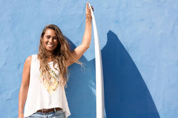 Boldog szörfös lány előtt kék fal szörfdeszka — Stock Fotó