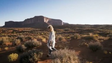 Monument Valley içinde kırmızı kayalar genel bakış ile yürüyen kadın.