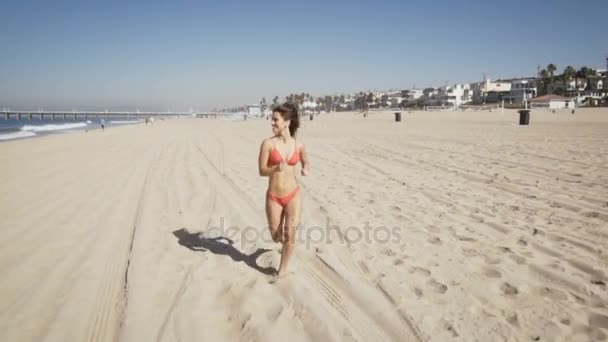 Szczęśliwa młoda kobieta działa w manhattan beach w Kalifornii. czas letni — Wideo stockowe