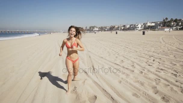 Heureuse jeune femme court à la plage de Manhattan en Californie. au ralenti — Video