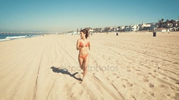 Heureuse jeune femme court à la plage de Manhattan en Californie. filtre vintage — Video